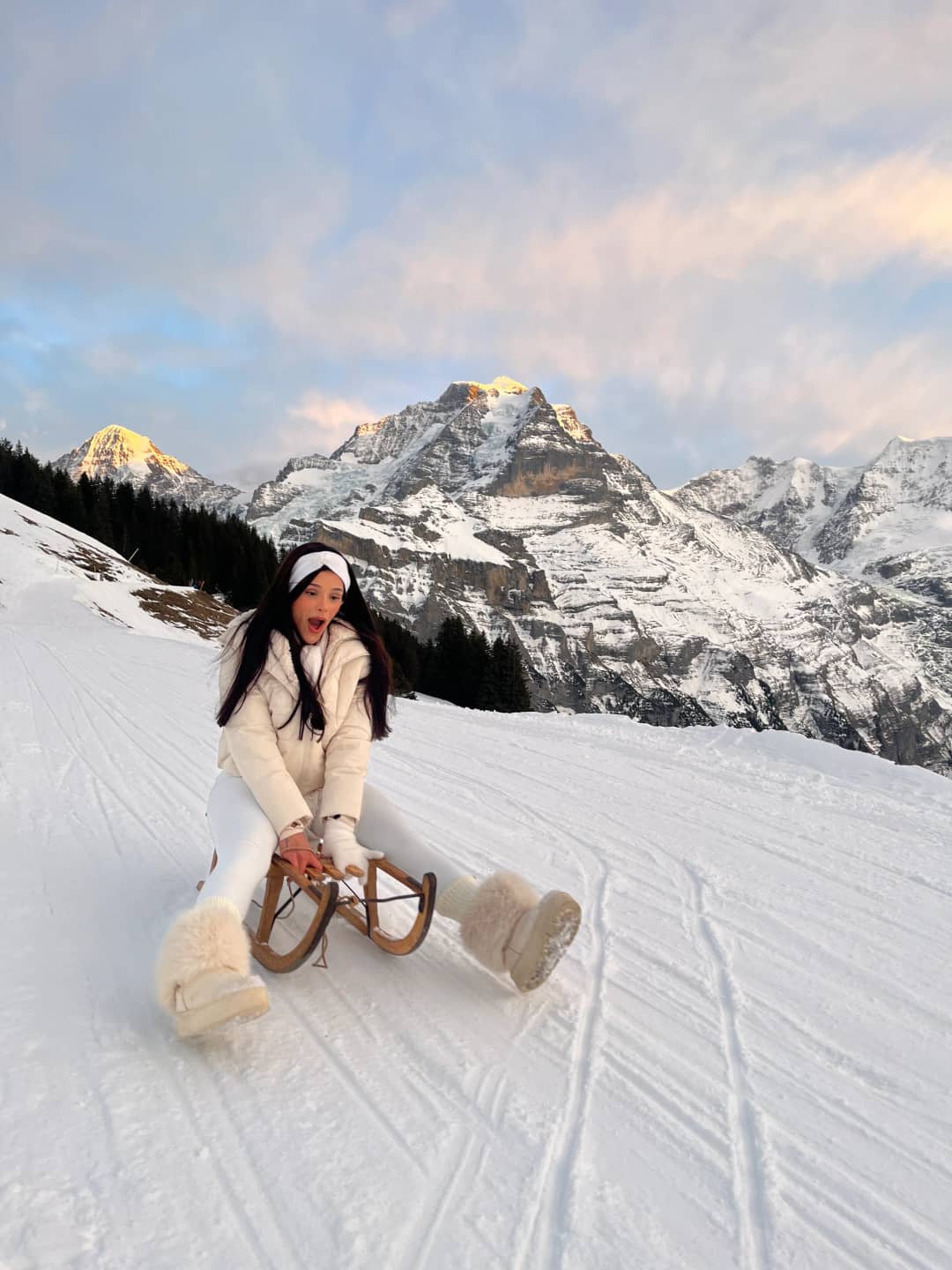 Schlitteln in Interlaken, Schlittenfahrt auf verschneitem Bergweg im Abendlicht der Jungfrau Region