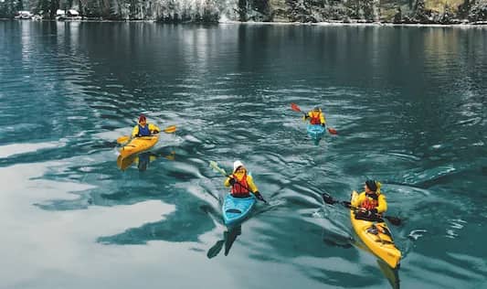 Kayak deslizándose sobre el agua turquesa del lago de Brienz frente a laderas nevadas