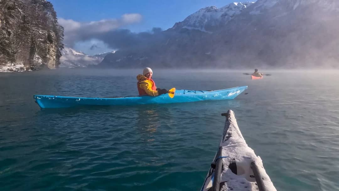 Dos personas en kayak remando juntas sobre el lago de Brienz bajo un cielo de invierno