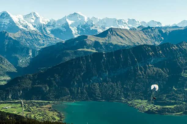 Paraglider soaring above Lake Thun with Eiger Mönch and Jungfrau in the background, tandem paragliding Interlaken