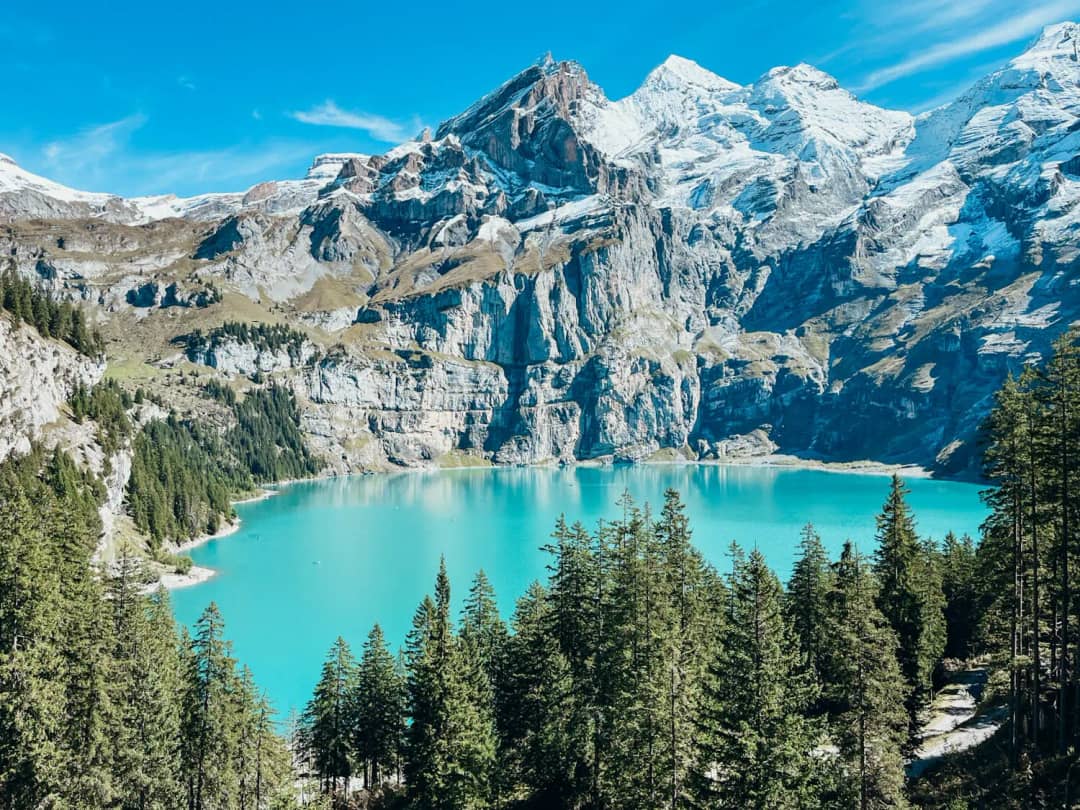 Lago de montaña Oeschinensee turquesa entre bosque alpino y las cumbres nevadas del Blüemlisalp, Kandersteg