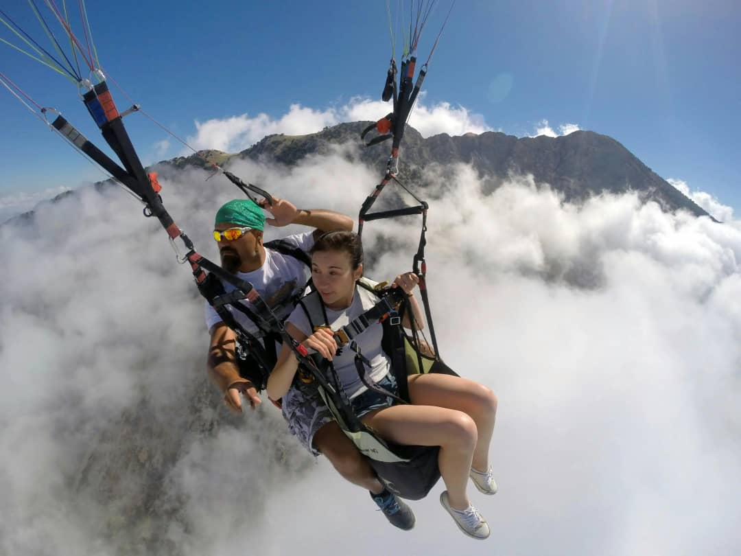 Tandem paragliding passenger and pilot flying above the clouds with alpine peaks in the background, Swiss Alps Interlaken