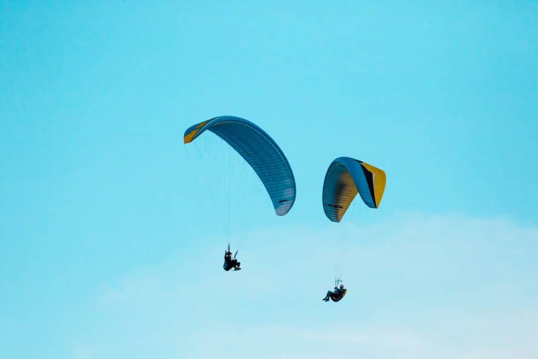 Two tandem paragliders with blue and yellow canopies sharing the sky above Interlaken, Bernese Oberland Switzerland