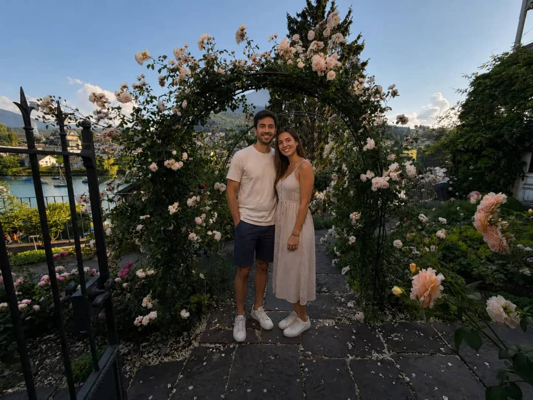 Smiling couple beneath a blooming rose arch in the Spiez Castle rose garden overlooking Lake Thun