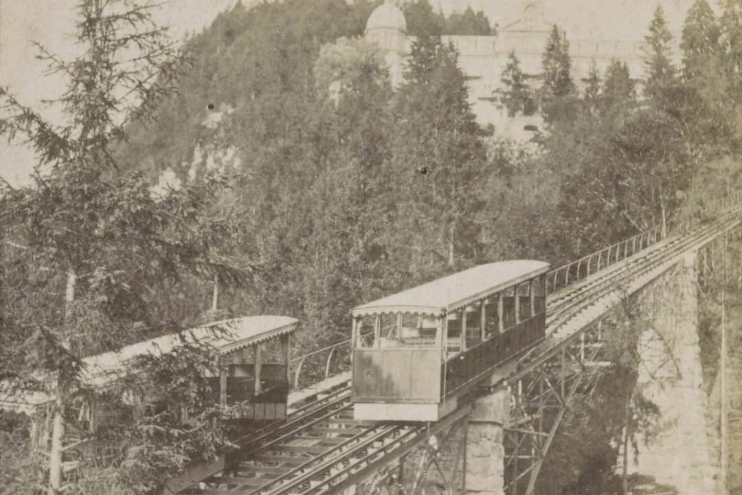 Nineteenth century sepia photograph of two Giessbach funicular cars on their track through the forest
