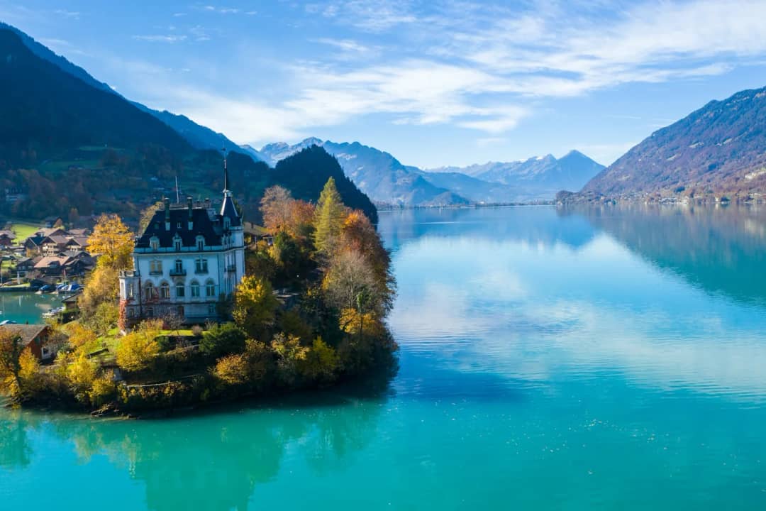Schloss Seeburg auf seiner kleinen bewaldeten Halbinsel bei Iseltwald, gespiegelt im ruhigen Herbstwasser