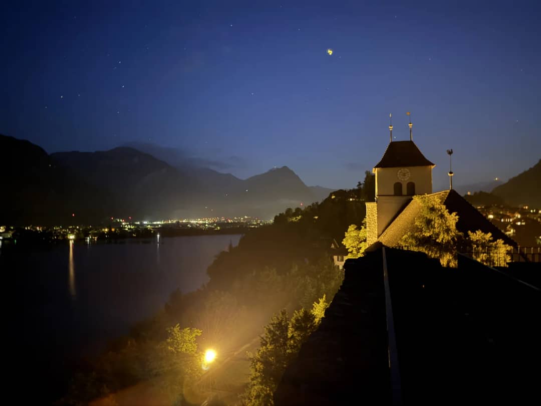 Die Burgkirche Ringgenberg nachts beleuchtet auf ihrem Felsen ĂĽber dem Brienzersee, Lichter am fernen Ufer