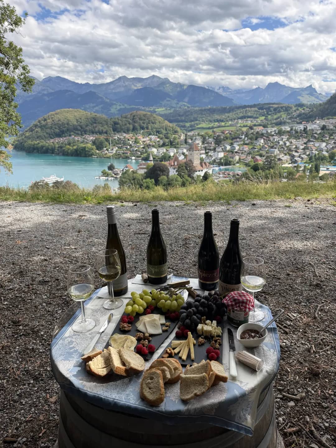 Vier Flaschen Spiezer und ein Käsebrett auf einem Fass über der Bucht, die Degustation der Weintour in Spiez