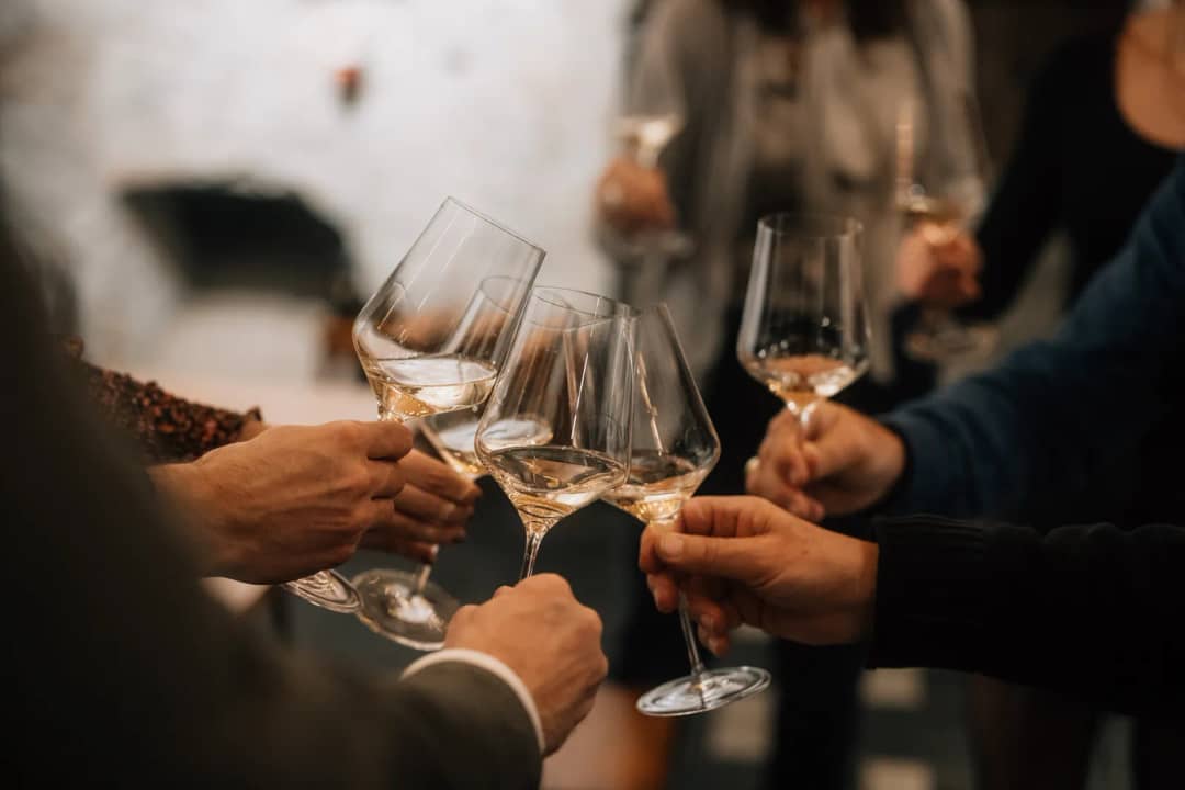 Verres de vin blanc levés pour trinquer à une dégustation à Spiez, verrerie et service compris à CHF 139