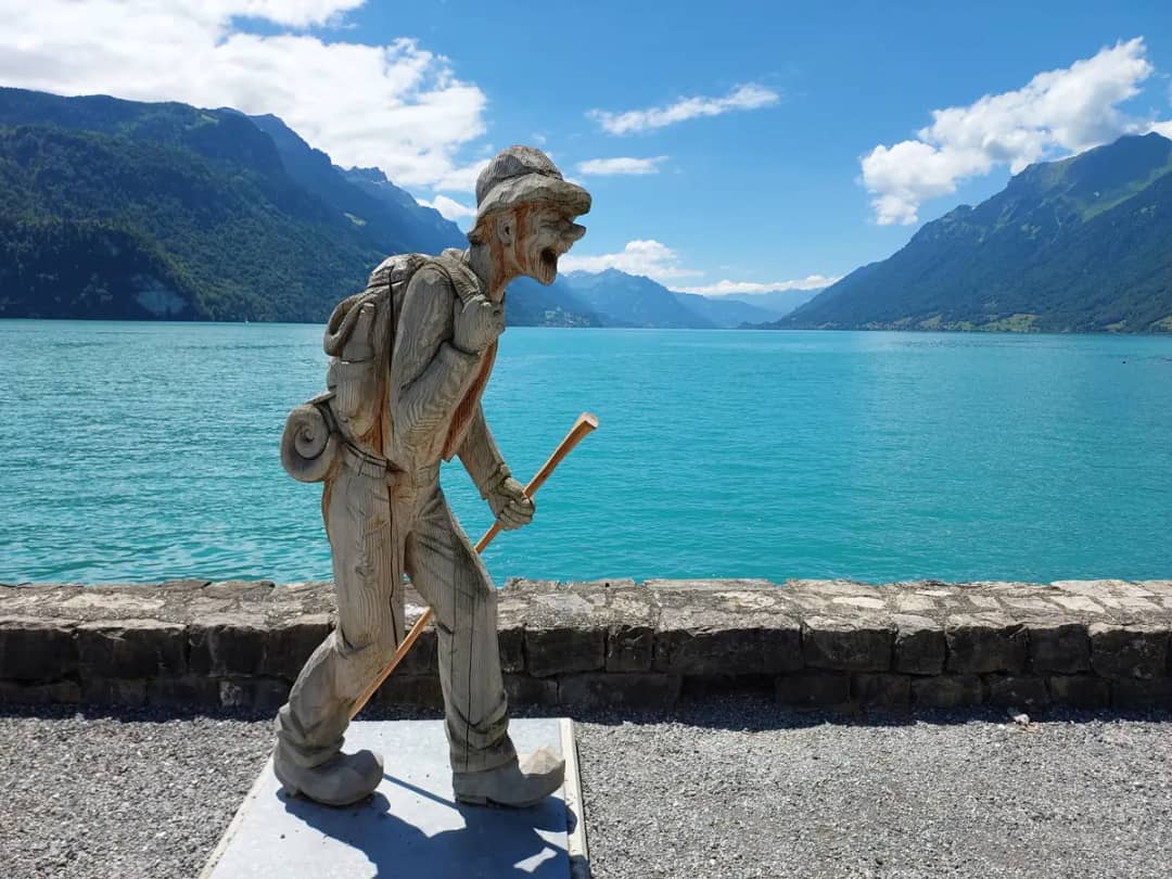 Geschnitzter Holzwanderer an der Seepromenade von Brienz, wo Sie vom Zug ins Postauto 155 zur Axalp umsteigen