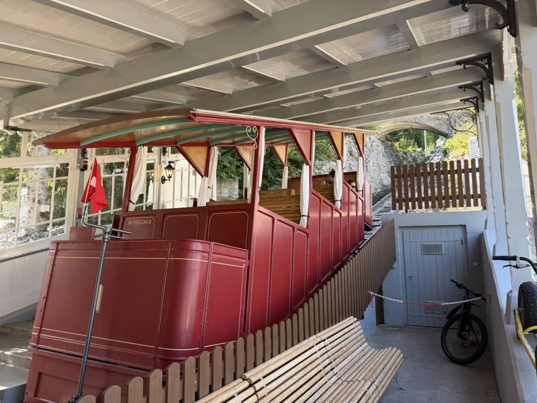 Red wooden carriage of the Reichenbach Falls funicular waiting under the roof of its Willigen valley station