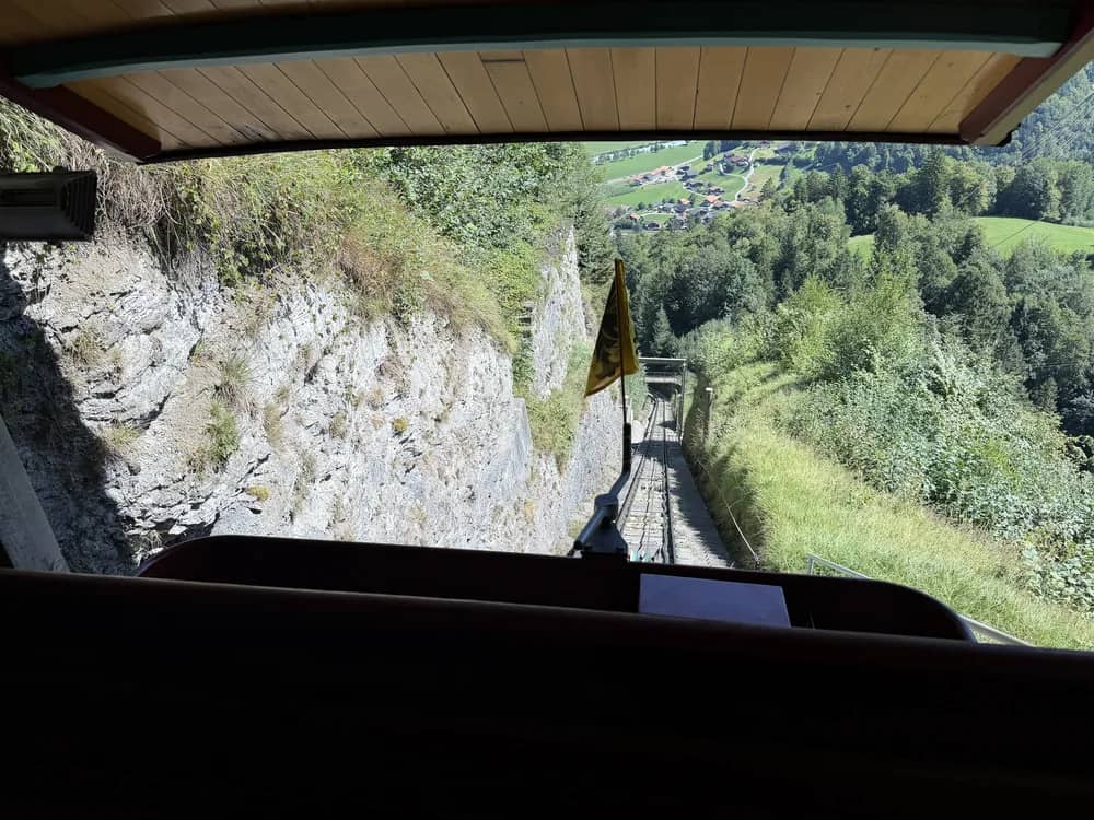 Blick aus dem Wagen der Reichenbachfall-Bahn die steile Strecke hinab, tief unten die Felder von Meiringen