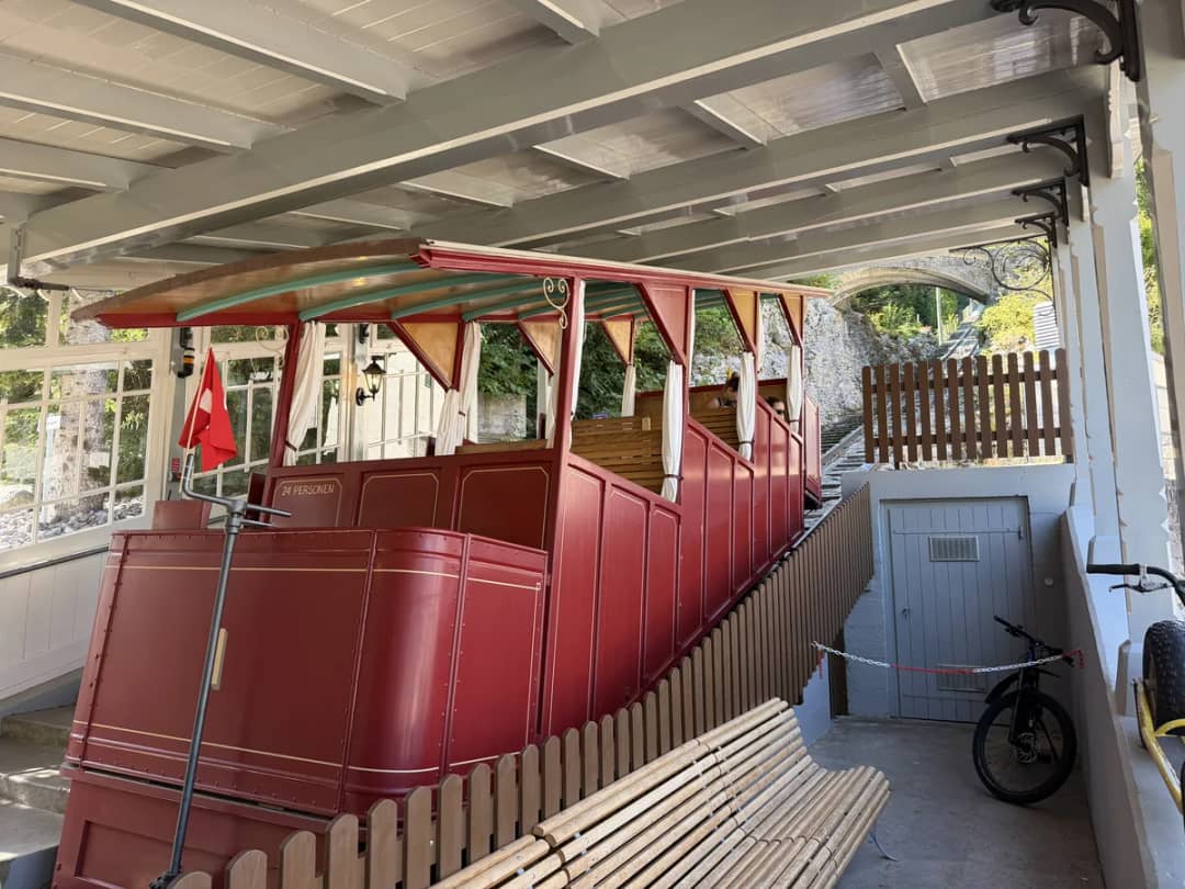 Roter Holzwagen der Reichenbachfall-Bahn unter dem Dach der Talstation bei Meiringen, bereit zur Bergfahrt