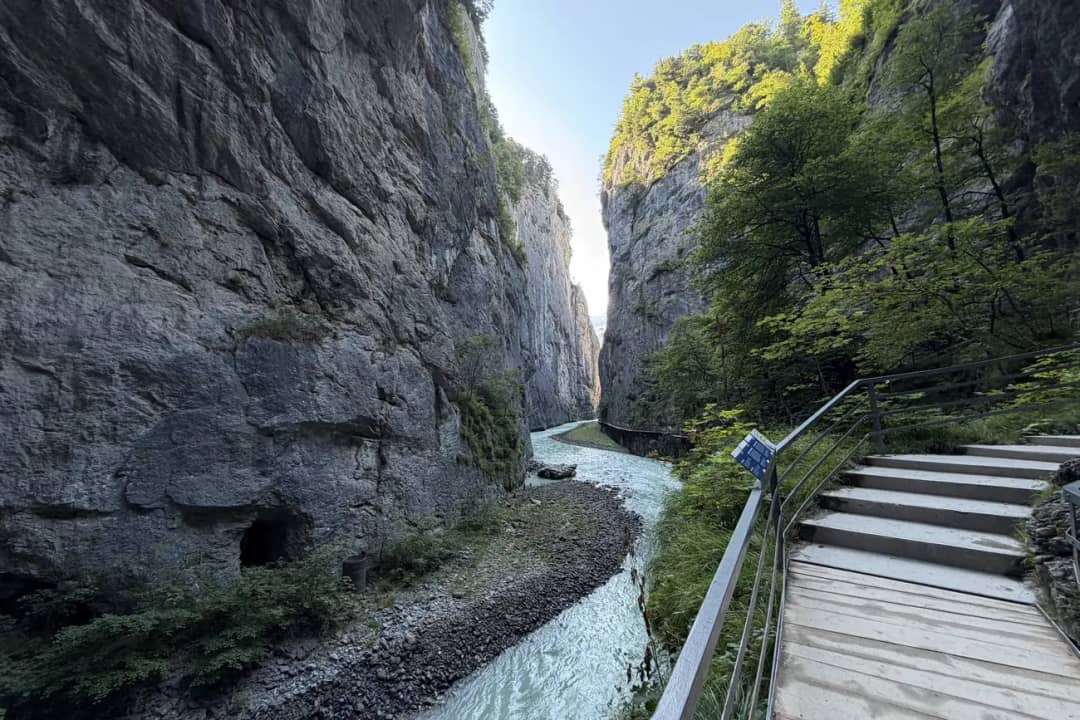 Turquoise Aare river running between tall limestone walls beside the wooden walkway inside the Aare Gorge