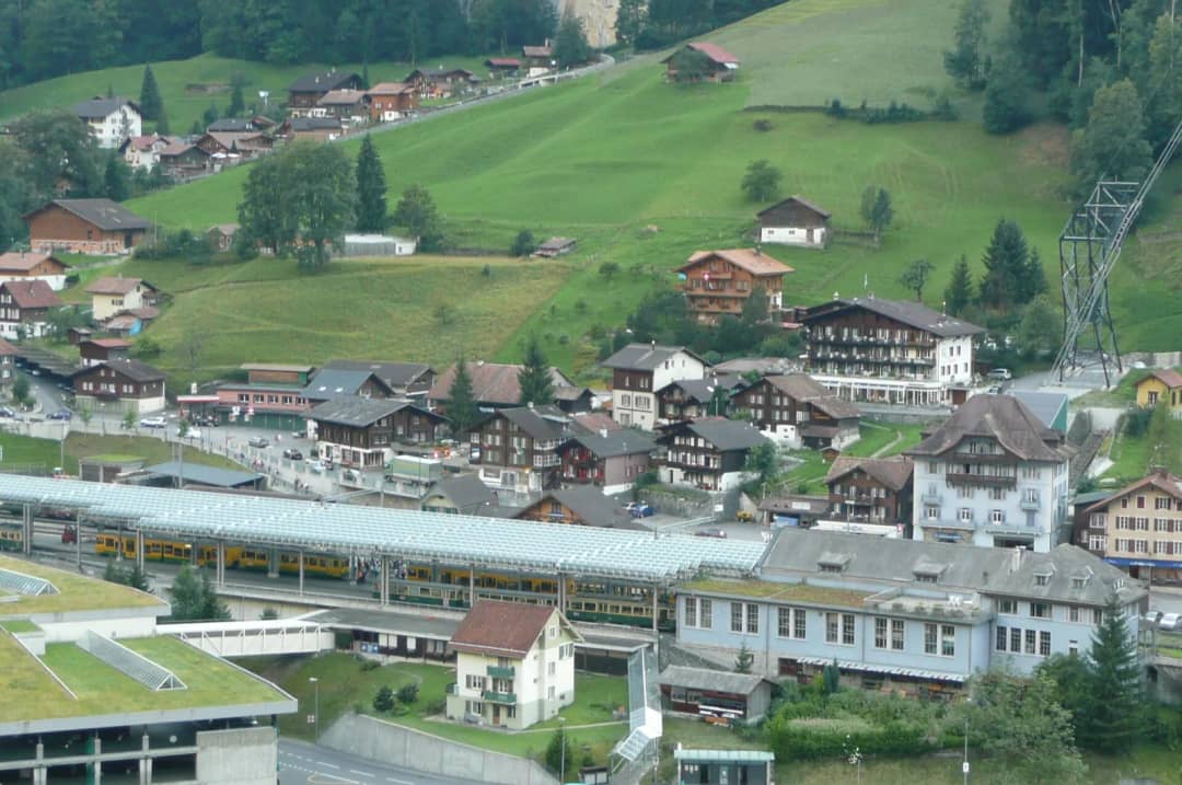 La estación de Lauterbrunnen con los trenes amarillos bajo la marquesina y el aparcamiento de la estación