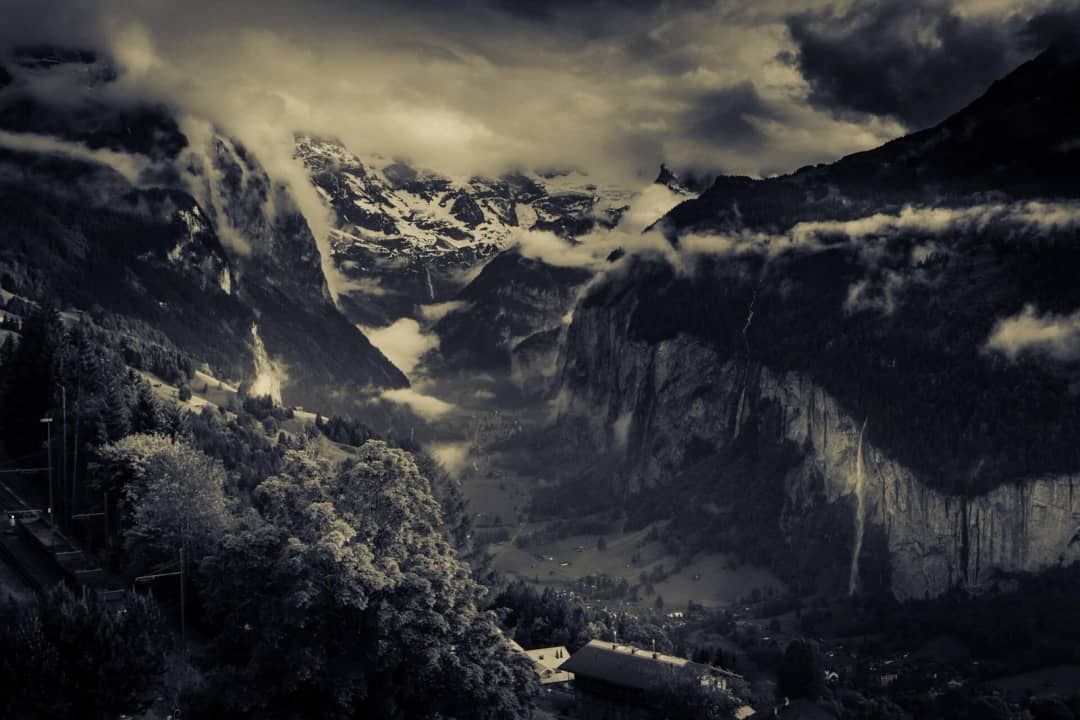 Las nubes llenan el valle de Lauterbrunnen entre los acantilados, con cascadas en la pared tras la lluvia