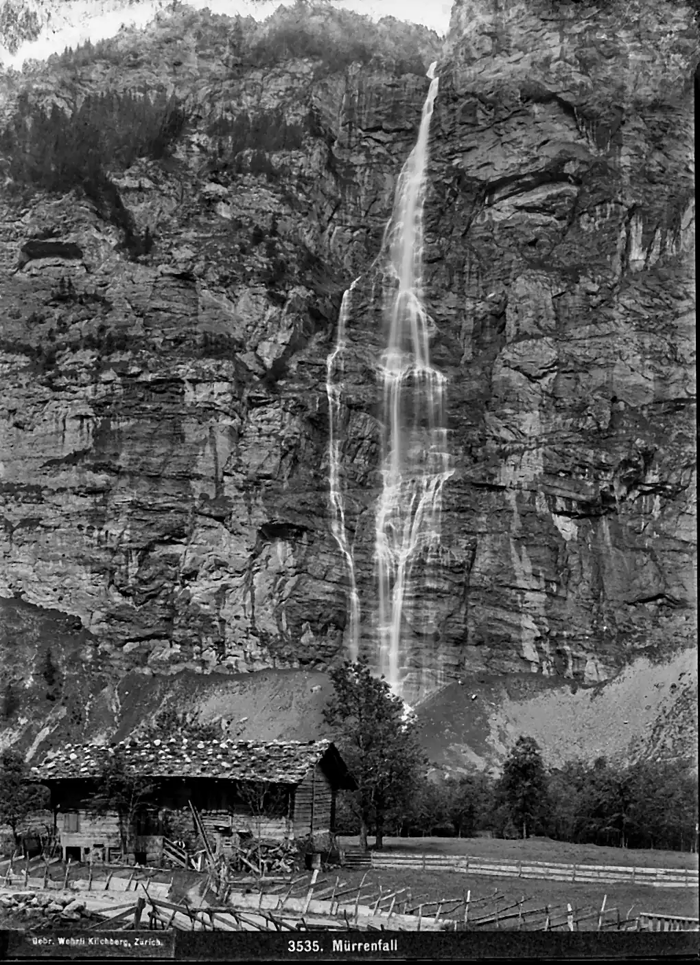 Historic photograph of the Mürrenbach waterfall falling down the cliff above a timber chalet near Stechelberg