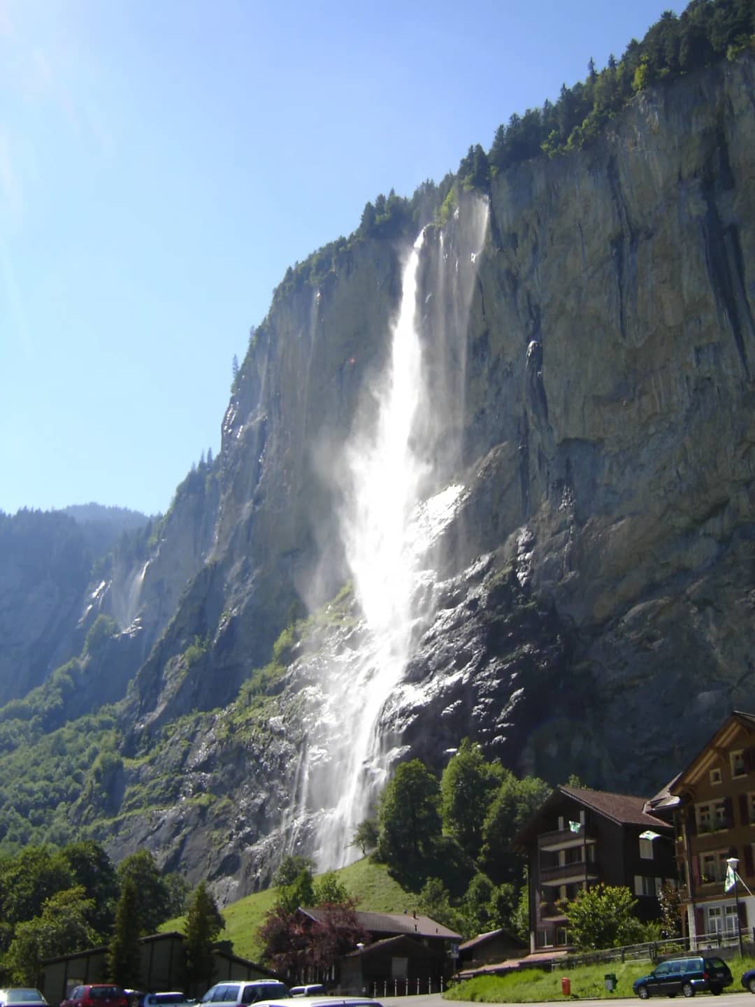 The Staubbach waterfall falling down the cliff above Lauterbrunnen in full summer flow under a blue sky