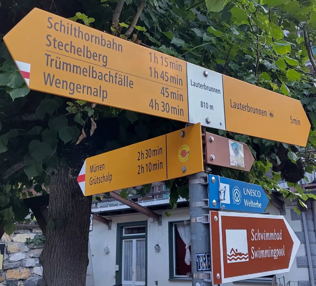 Yellow Swiss hiking signpost in Lauterbrunnen pointing to Trümmelbachfälle, Stechelberg and Mürren