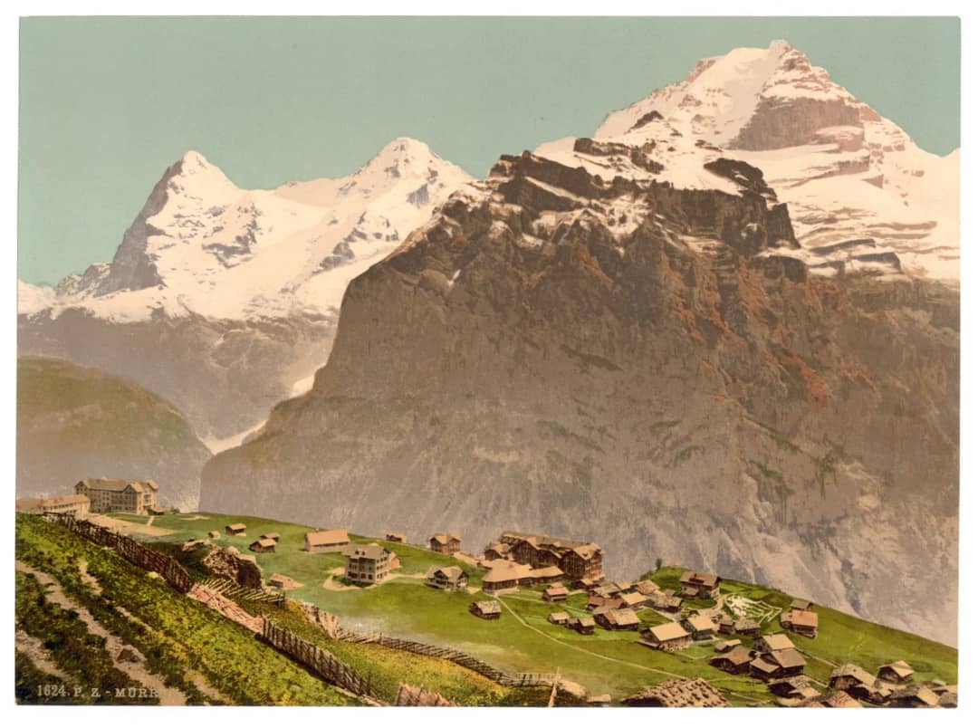 Una fotocromía de Mürren en la década de 1890 con el Eiger y el Mönch detrás de los tejados del pueblo