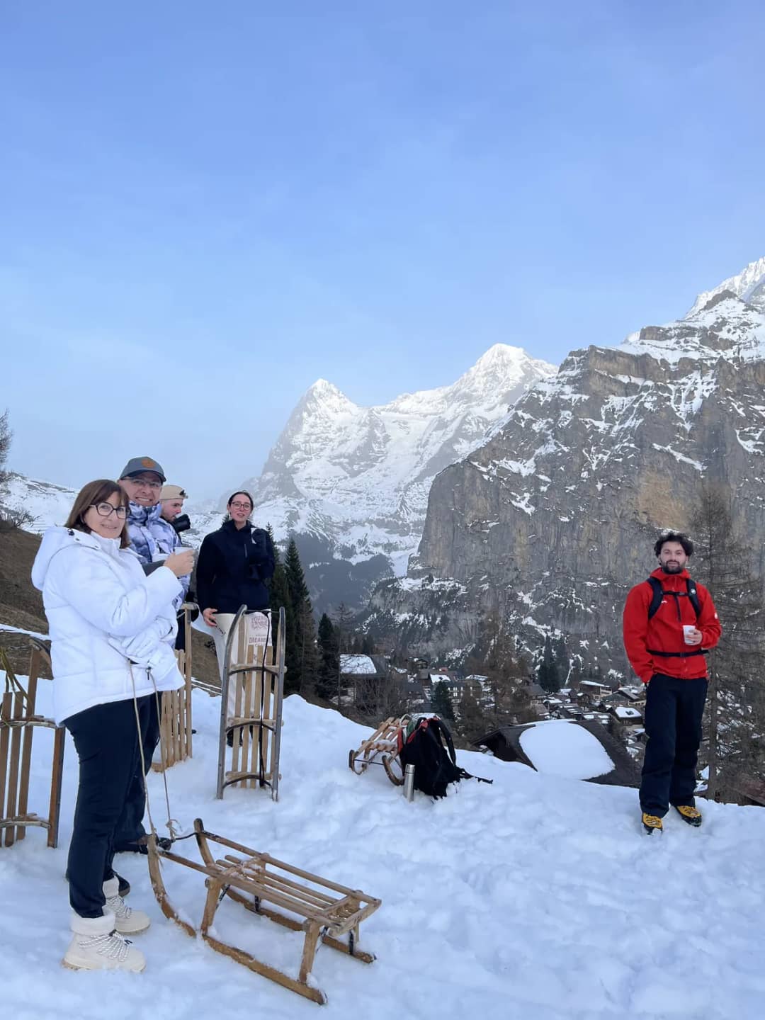 Sledders on a snowy slope at Mürren in March 2026, with the peaks across the Lauterbrunnen valley behind them