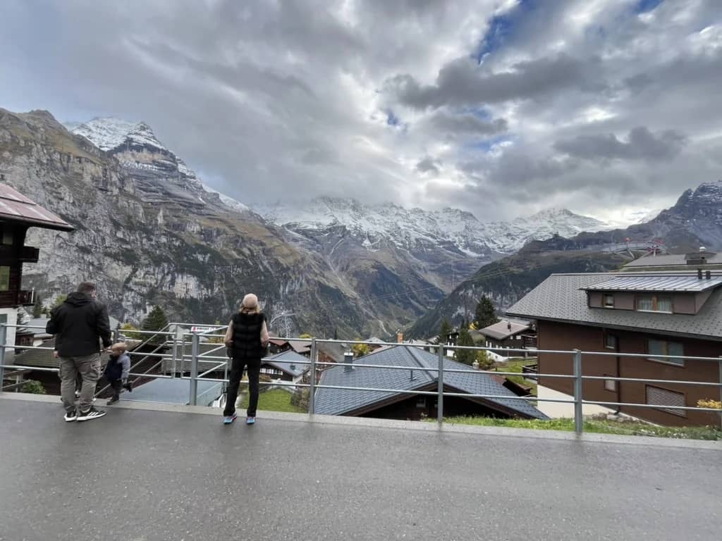 Visitors on a village street in Mürren in mid October, looking across the Lauterbrunnen valley to snowy peaks