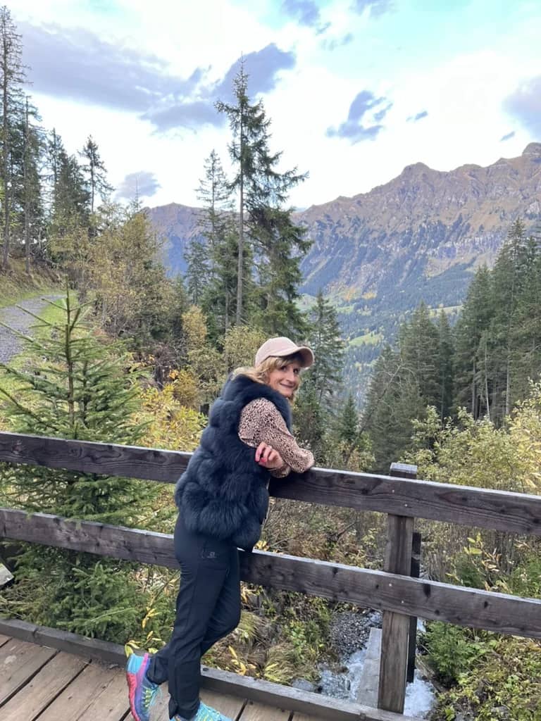 A traveller leaning on a wooden bridge rail among autumn firs above the Lauterbrunnen valley in mid October