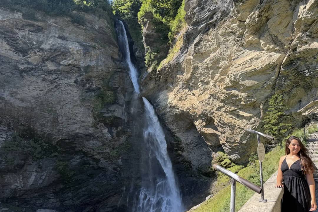 Une visiteuse près des chutes du Reichenbach, à Meiringen, en été, l'eau plongeant dans une gorge ensoleillée