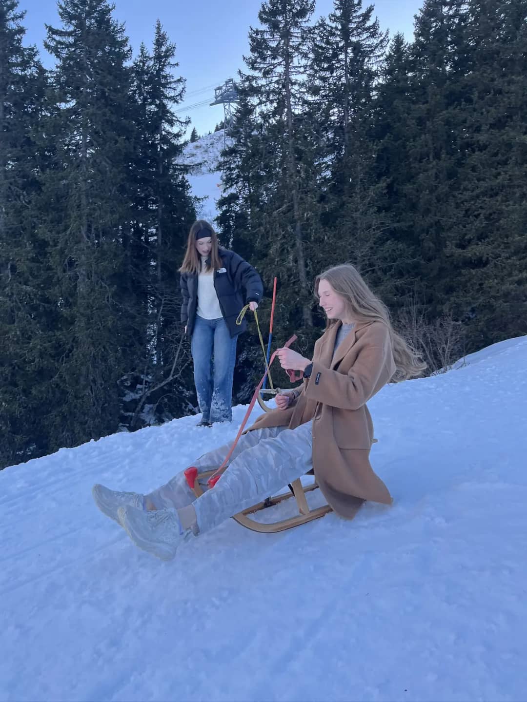 Dos personas en trineos de madera en el bosque nevado sobre Mürren, una pista fácil para hacer trineo por su cuenta