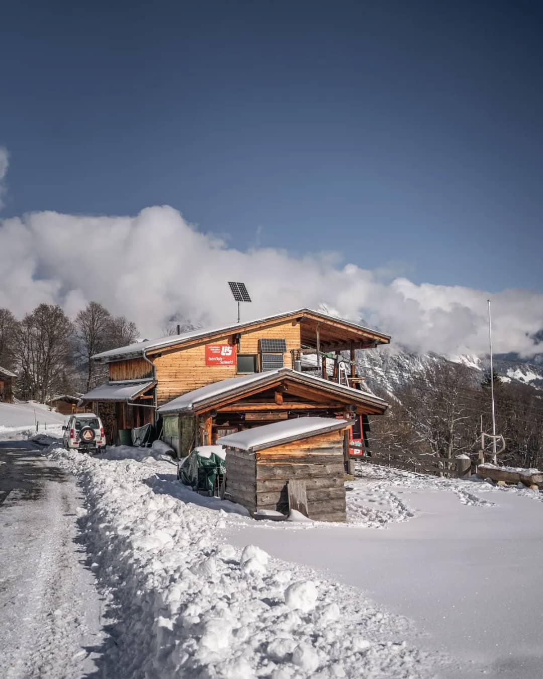 Hoch aufgetürmter Schnee um die hölzerne Bergstation der Seilbahn Isenfluh in Sulwald, Wolken über den Gipfeln