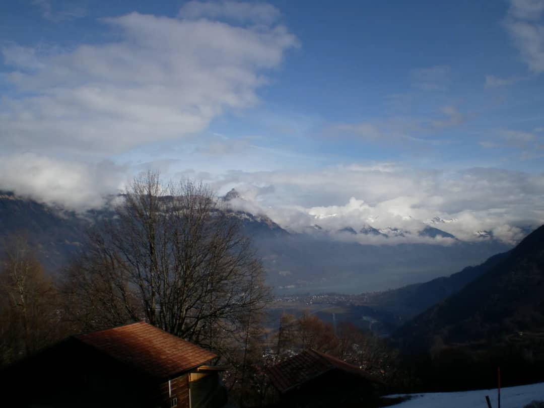 Vista desde Saxeten, pueblo de raquetas, en febrero: tejados de chalets, Interlaken y el lago de Brienz