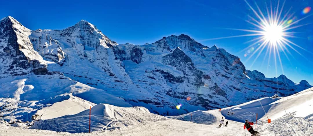 Die Lauberhorn-Piste über Wengen bei blauem Himmel mit Eiger, Mönch und Jungfrau, Skigebiete bei Interlaken