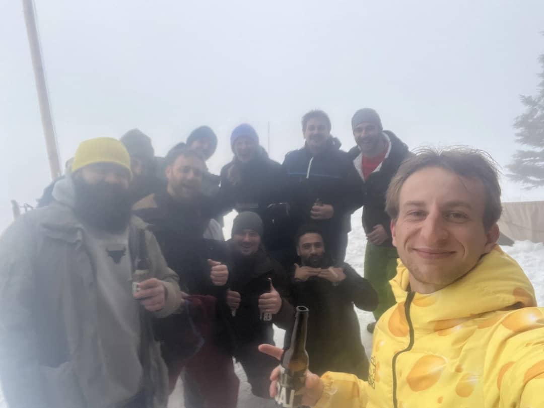 A sledding group in winter jackets and beanies poses for a selfie in thick fog on the snow above Mürren