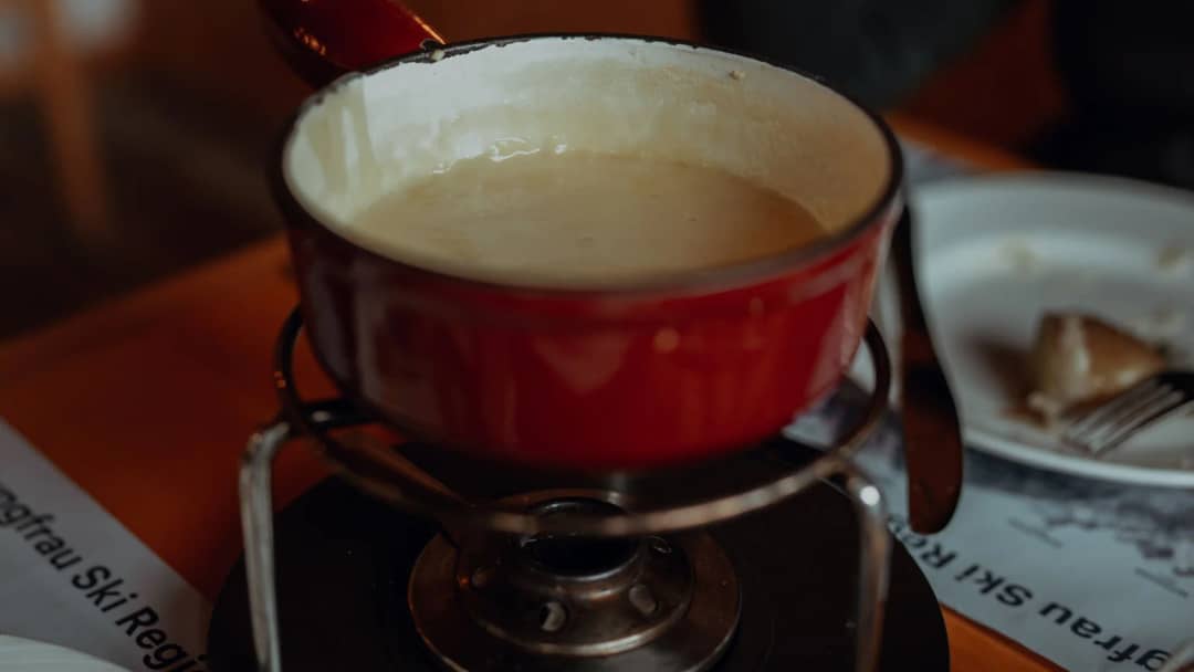 Fondue à Interlaken : une fondue au fromage dans un caquelon rouge sur son réchaud, sur un set Jungfrau Ski Region
