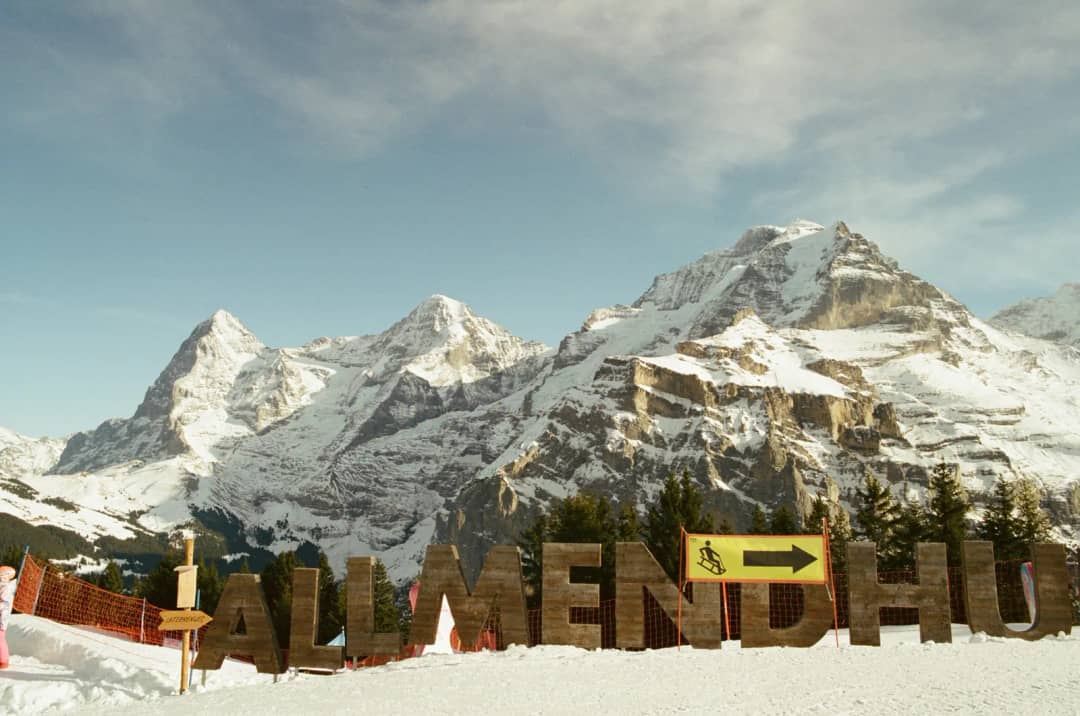 Giant wooden letters spell Allmendhubel where the Bob Run starts, with the Eiger and Jungfrau behind