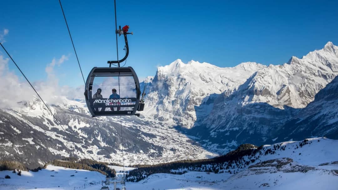 Eine Männlichen-Gondel steigt über das verschneite Tal von Grindelwald, ein Winterausflug ab Interlaken