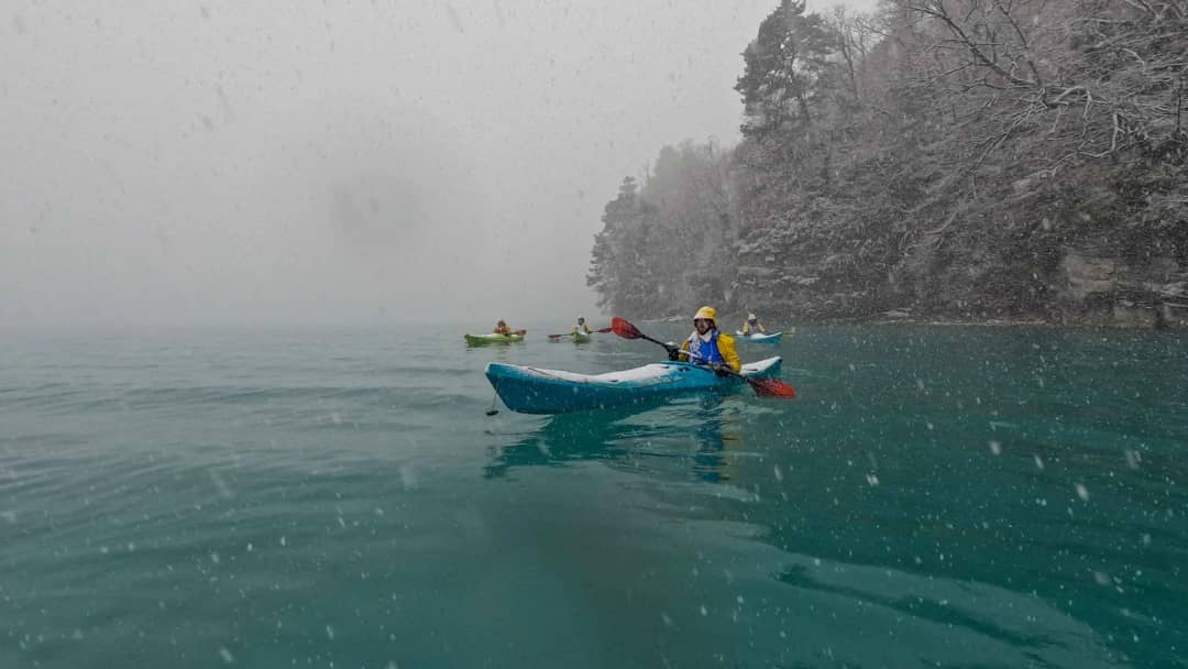 Kayakista con chaleco rojo entre la niebla matinal del lago de Brienz, kayak en invierno cerca de Bönigen