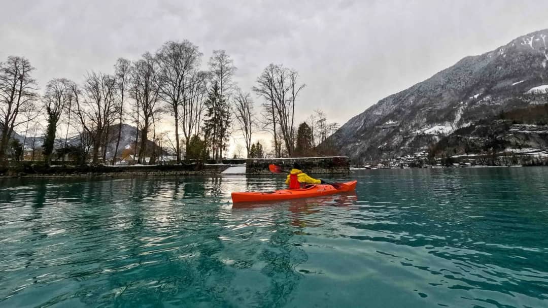 Dos kayaks de mar cruzan el lago de Brienz entre la niebla matinal, con sol bajo de invierno cerca de Bönigen
