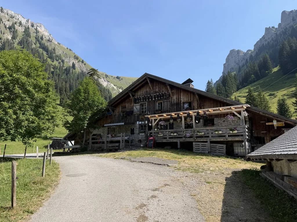 Wooden alpine farmhouse with flower boxes on the balcony along a gravel road in the Justistal, cliffs above