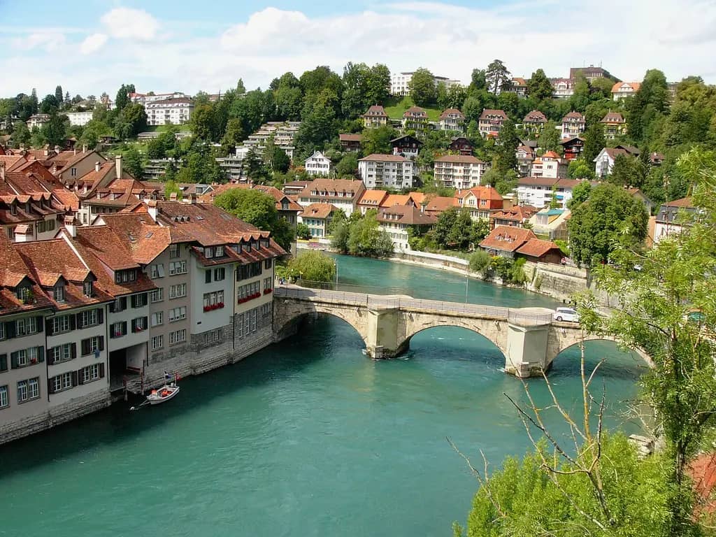 Steinerne Bogenbrücke über die grüne Aare in der Berner Altstadt, rote Ziegeldächer an beiden Flussufern