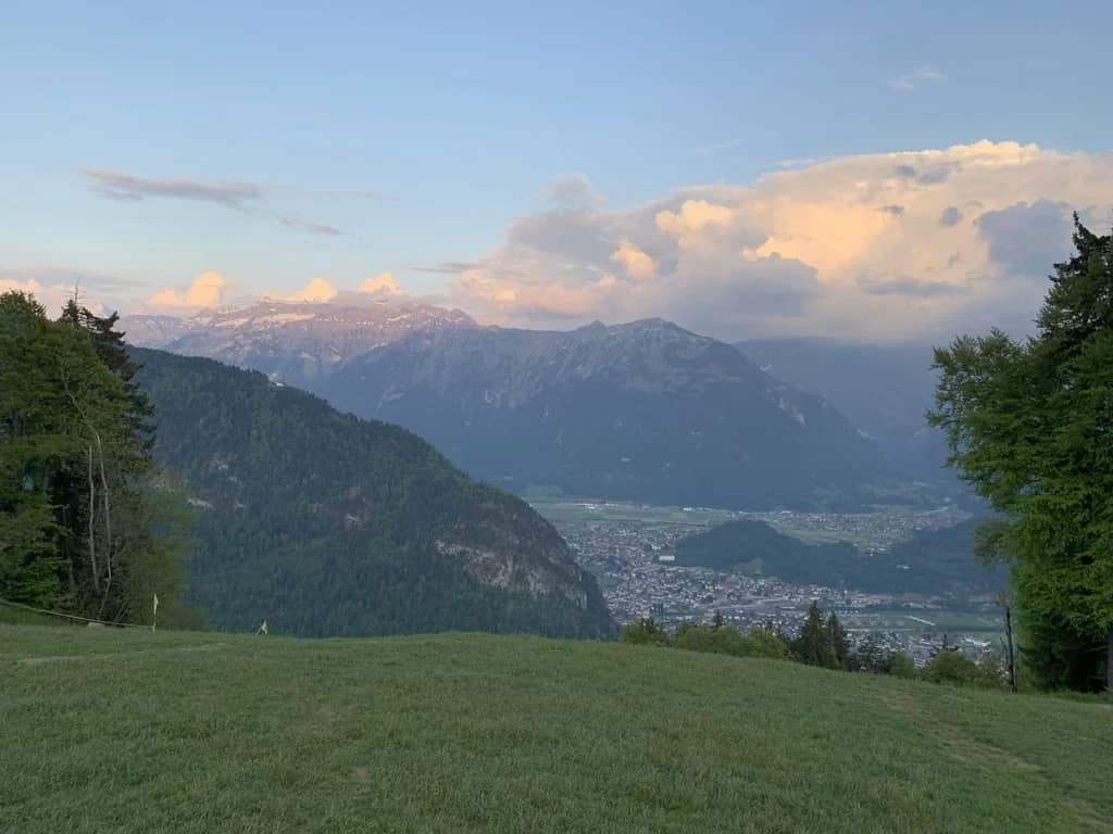 Interlaken et sa vallée vues depuis un pré en hauteur au crépuscule, lumière rose sur les hauts sommets