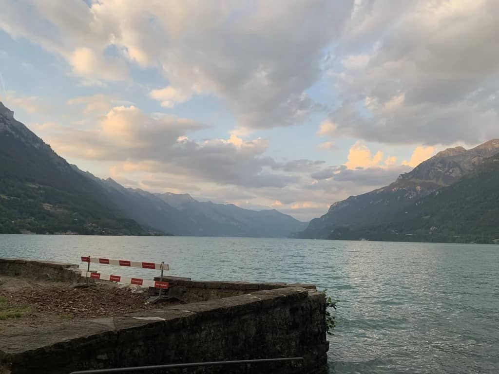 Brienzersee in der Abenddämmerung vom Ufer in Bönigen, rosa Wolken über den Bergen und eine alte Steinmauer