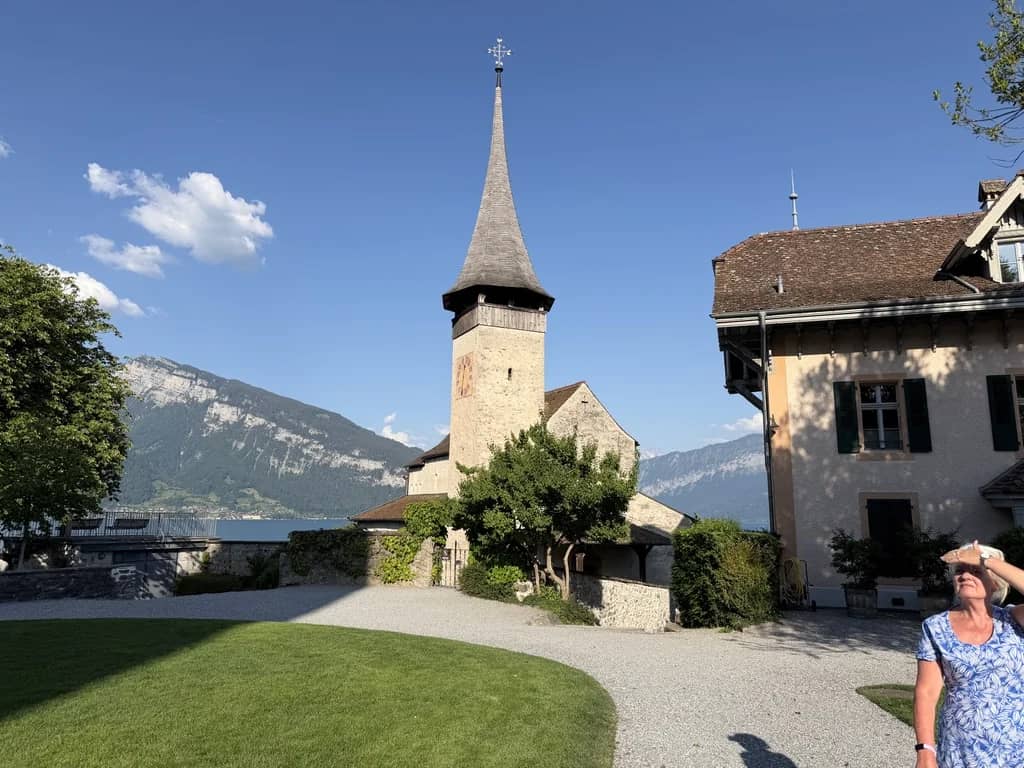 Clocher de l'église du château de Spiez et sa flèche élancée au-dessus de la pelouse, lac de Thoune derrière