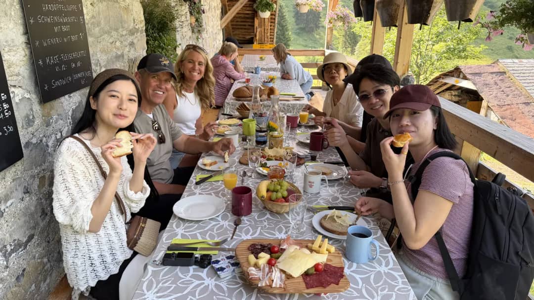 Farm Tour guests sharing an alpine breakfast of cheese, cured meat and bread on a Justistal farm terrace