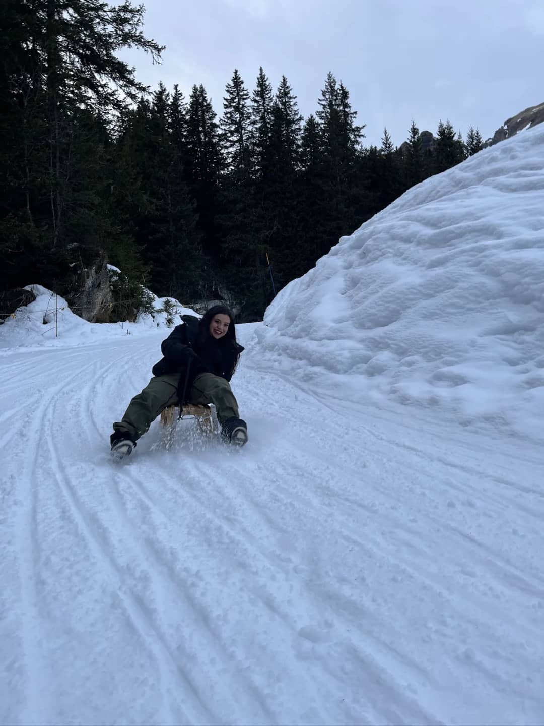 Persona sola en un trineo de madera baja por la pista pisada de la Bob Run en Mürren, hacer trineo sin guía al anochecer