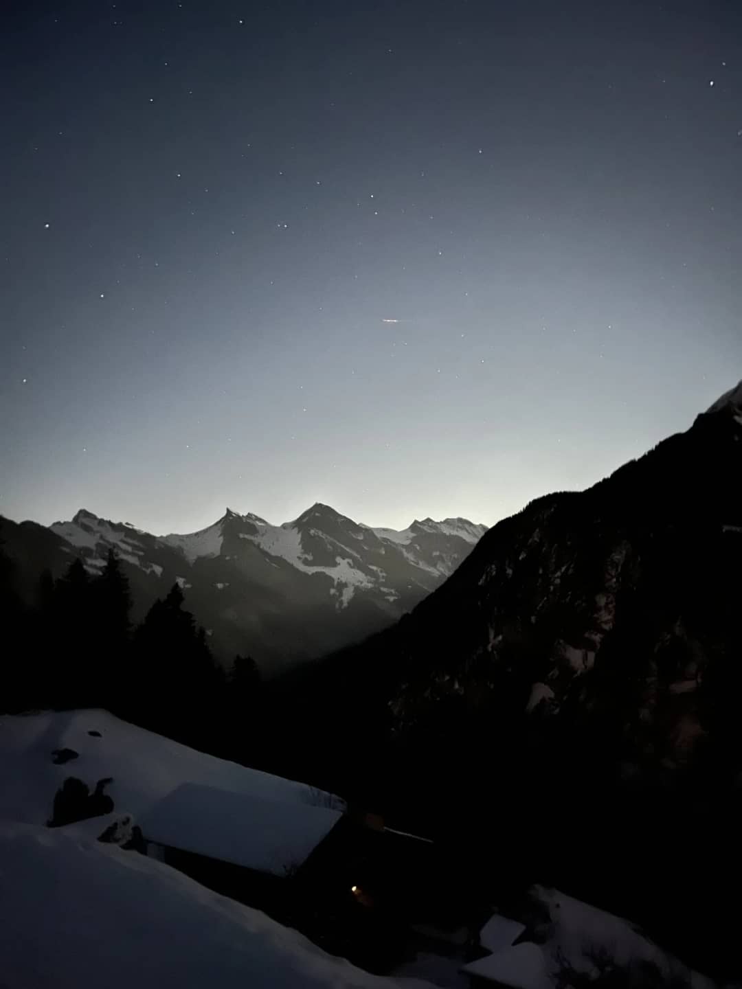 Tejados nevados de chalés en Isenfluh de noche sobre el oscuro valle de Lauterbrunnen, el final de la pista de trineo