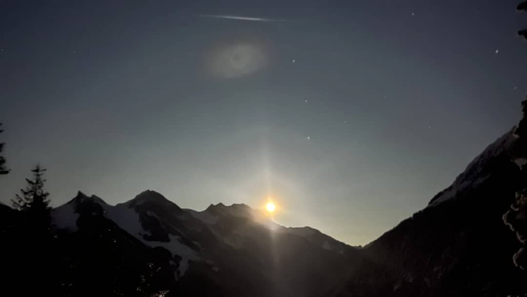 Luna llena sobre cumbres nevadas encima del valle de Lauterbrunnen de noche, vista desde la pista de trineo de Isenfluh