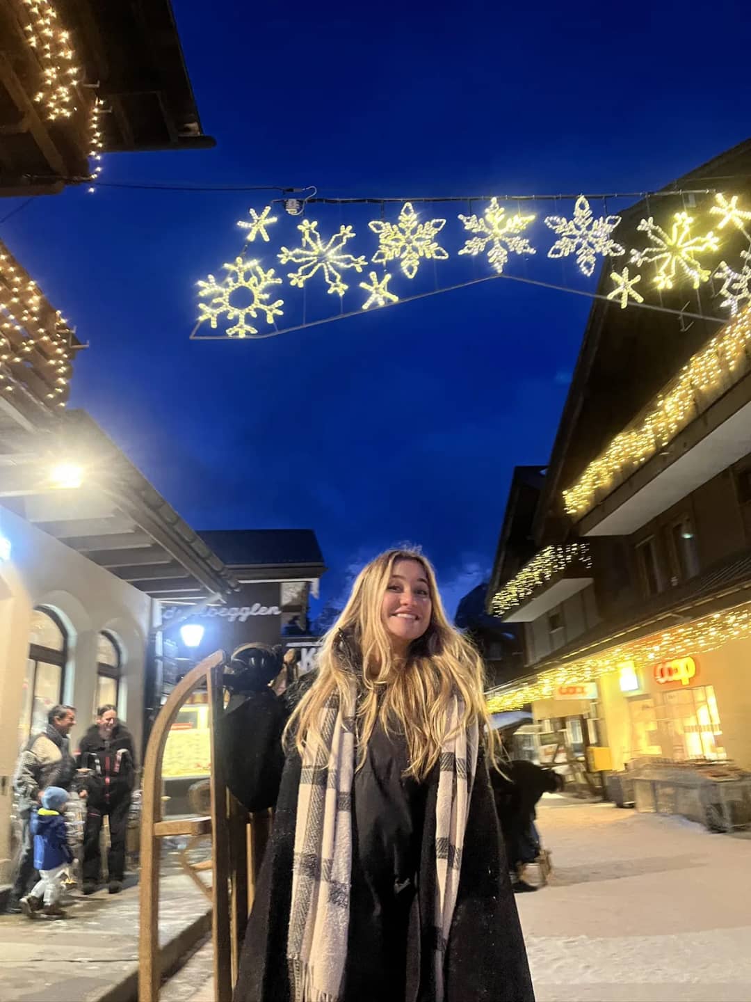 Sleds and visitors on Mürren's car-free main street under winter lights on a February evening