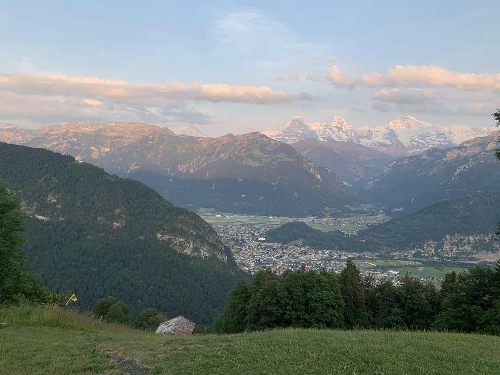 Eiger, Mönch and Jungfrau tinted pink above the town of Interlaken seen from the slope above Unterseen at dusk