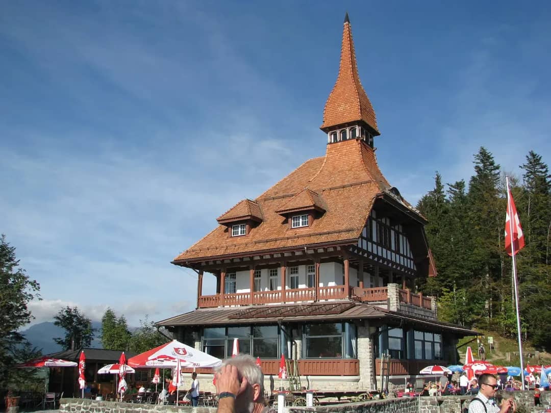 Harder Kulm panorama restaurant with its pointed tower and flags on the terrace above Interlaken in autumn